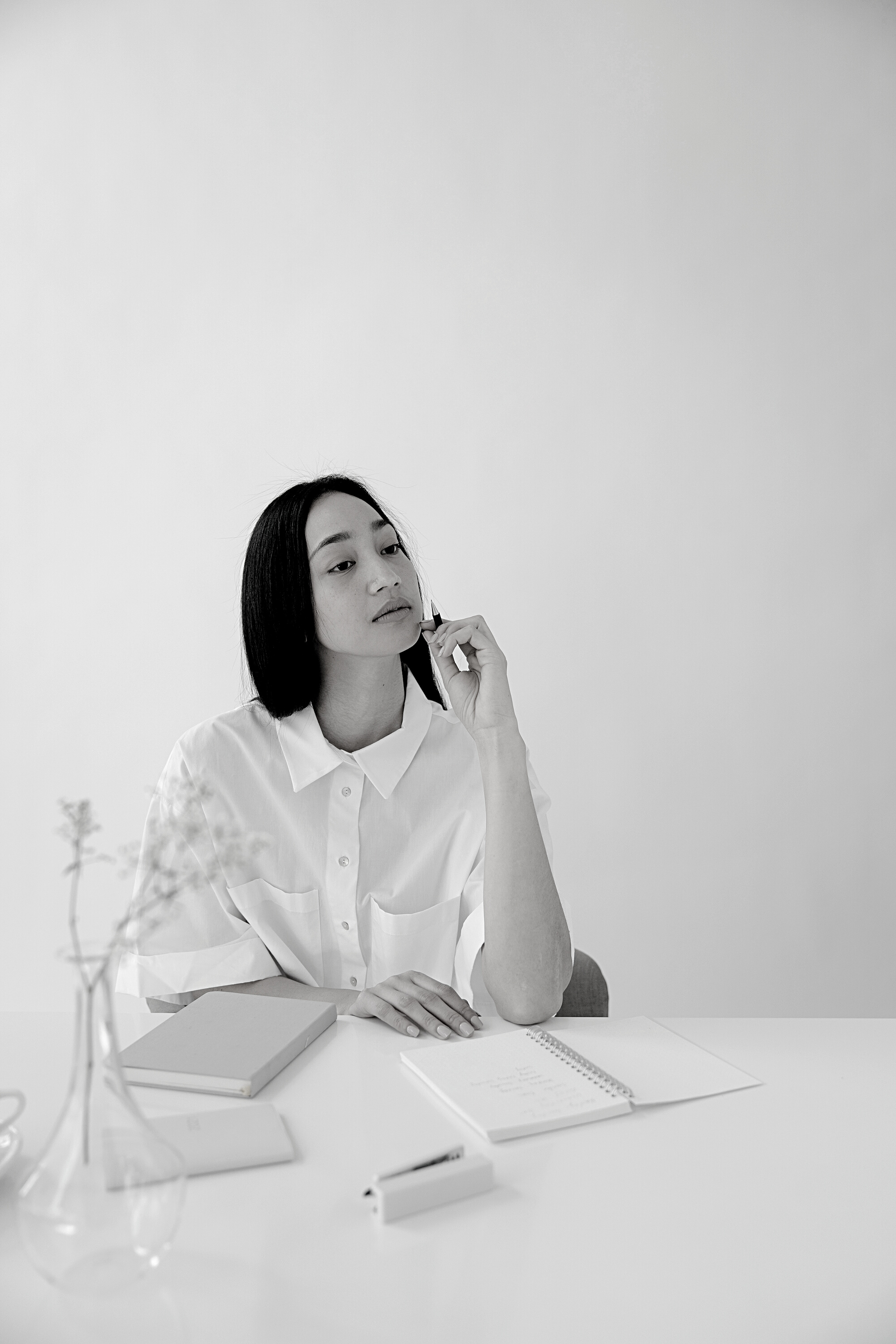 Thoughtful Asian employee with agendas at office table