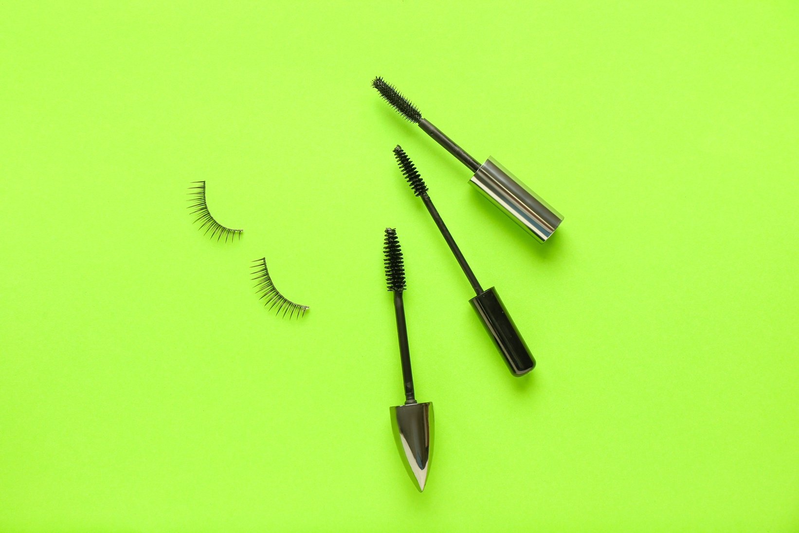 Mascara Wands and Fake Eyelashes on Green Background